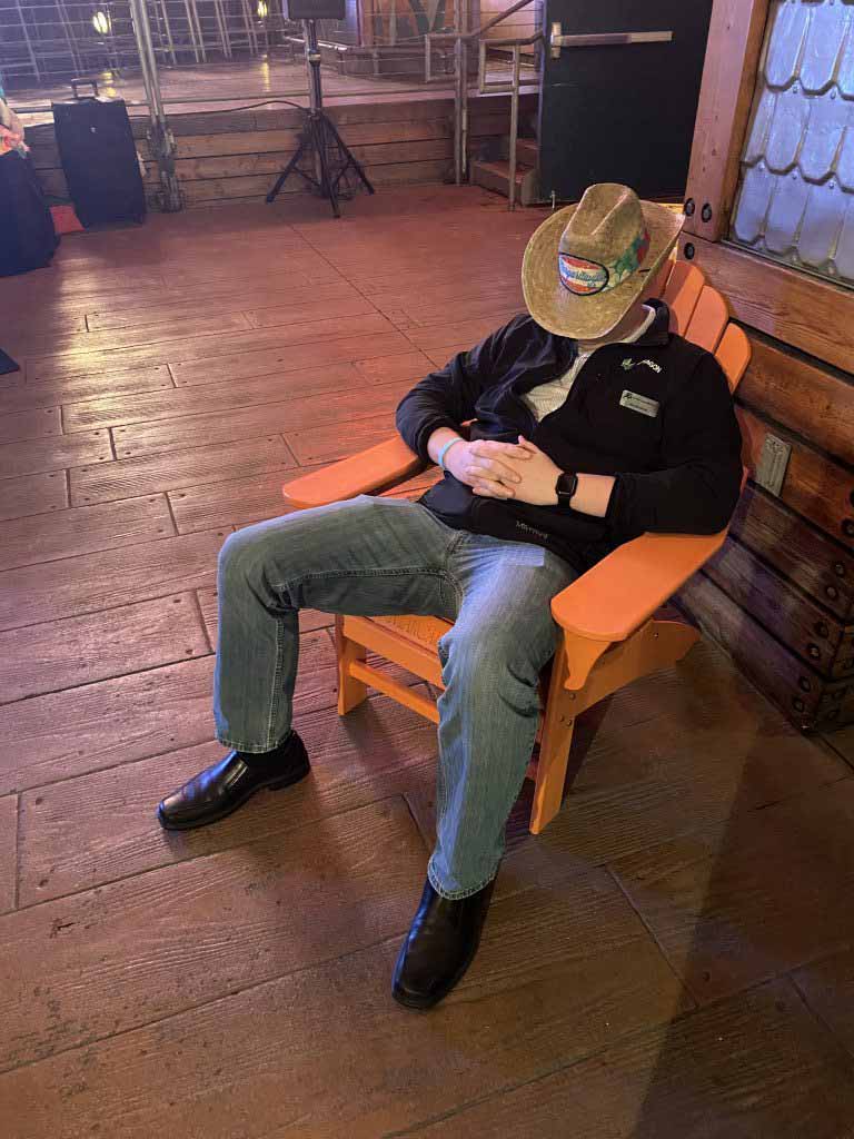 A man sitting in a chair with hat over his face